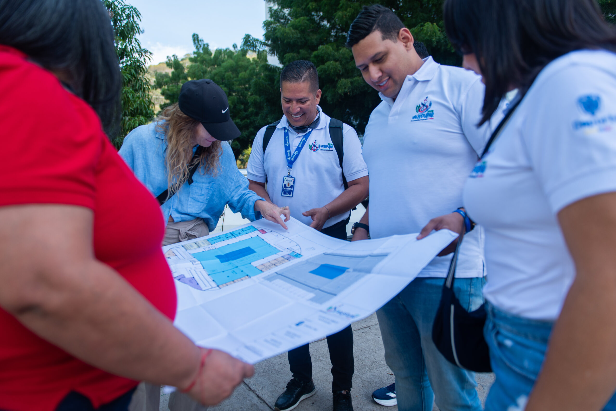 En la foto aparecen 5 personas, dos hombres y tres mujeres, viendo un plano de accesibilidad de un recinto deportivo.