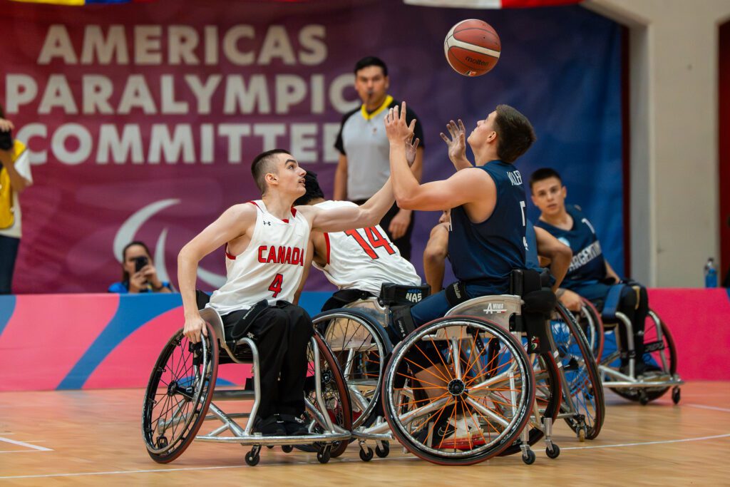 Enl a foto: dos jugadores de baloncesto en silla de ruedas disputando el balón.