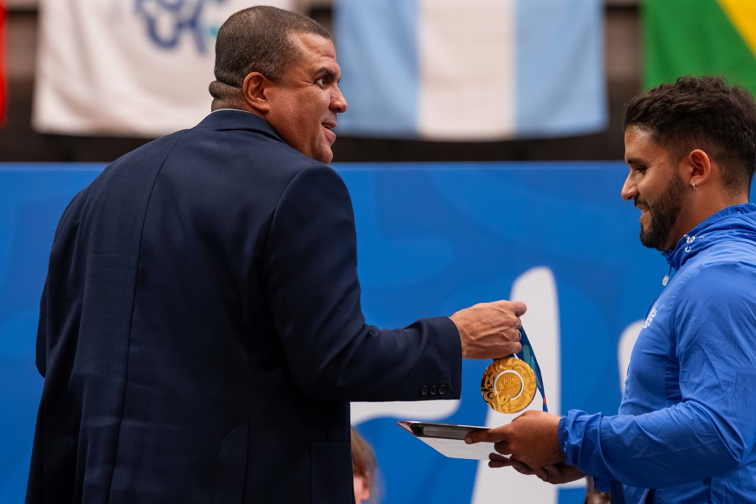 El Presidente sonrie mientras saca una medalla en premiación